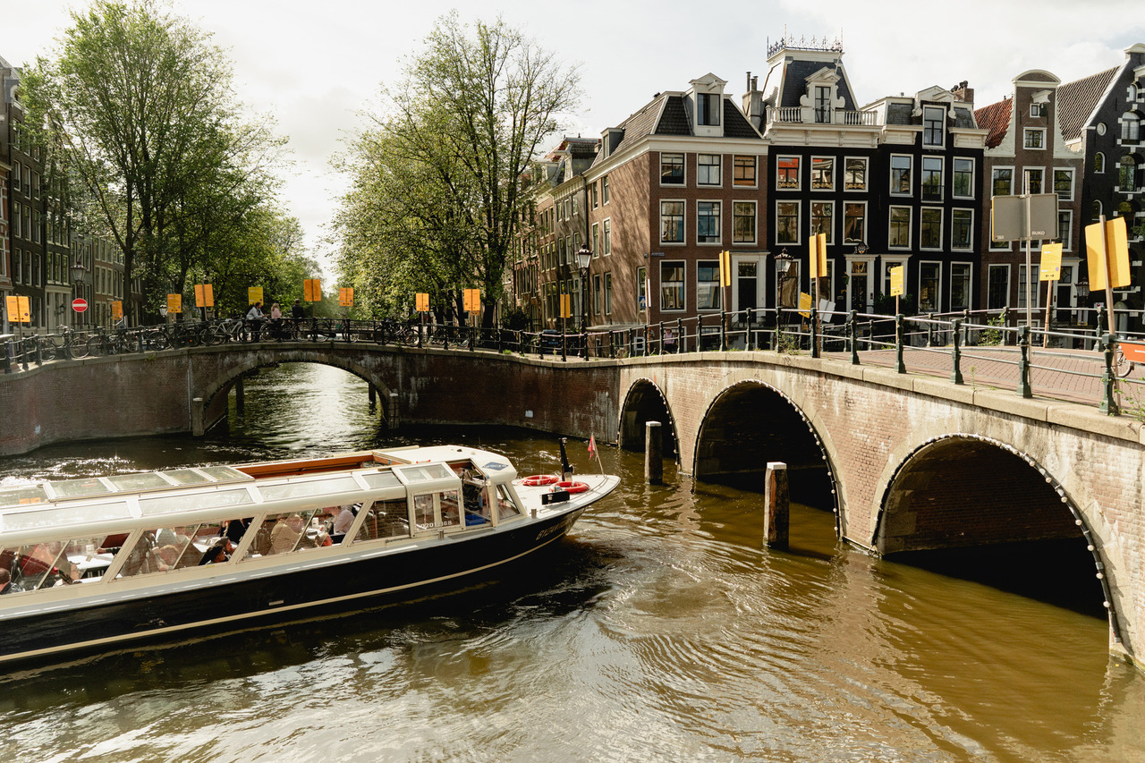 Yellow temporary notices along a bridge on Leidsegracht, with Amsterdam canal houses behind it.