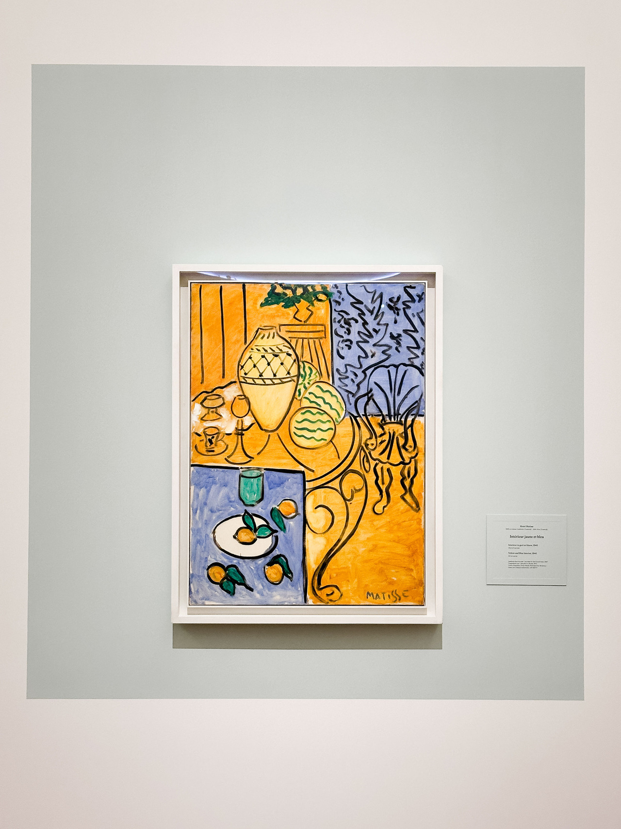 Yellow and Blue Interior by Henri Matisse, 1946, with lemons on a plate, a vase and furniture defined by strong black outlines.