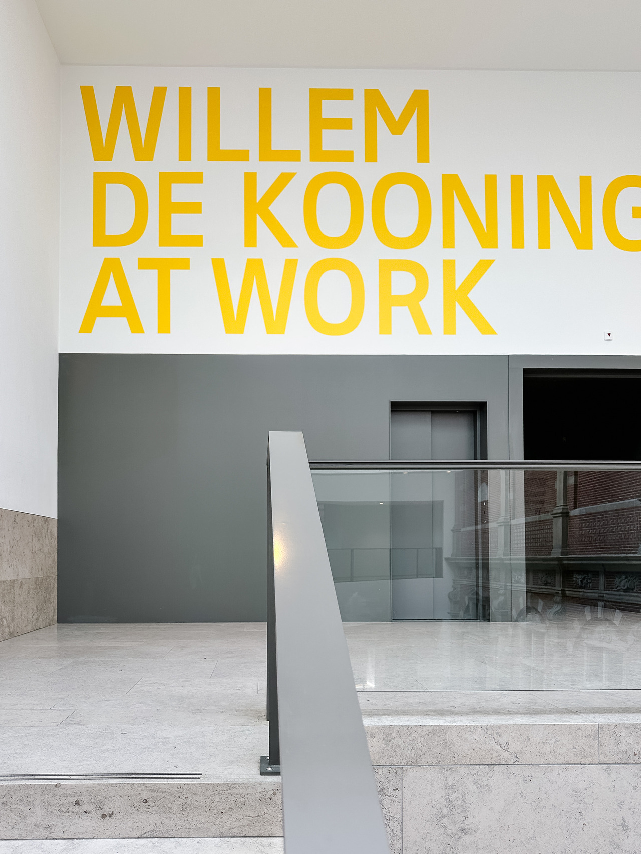 Entrance to Willem de Kooning at Work at the Rijksmuseum, with large yellow exhibition lettering above the staircase.