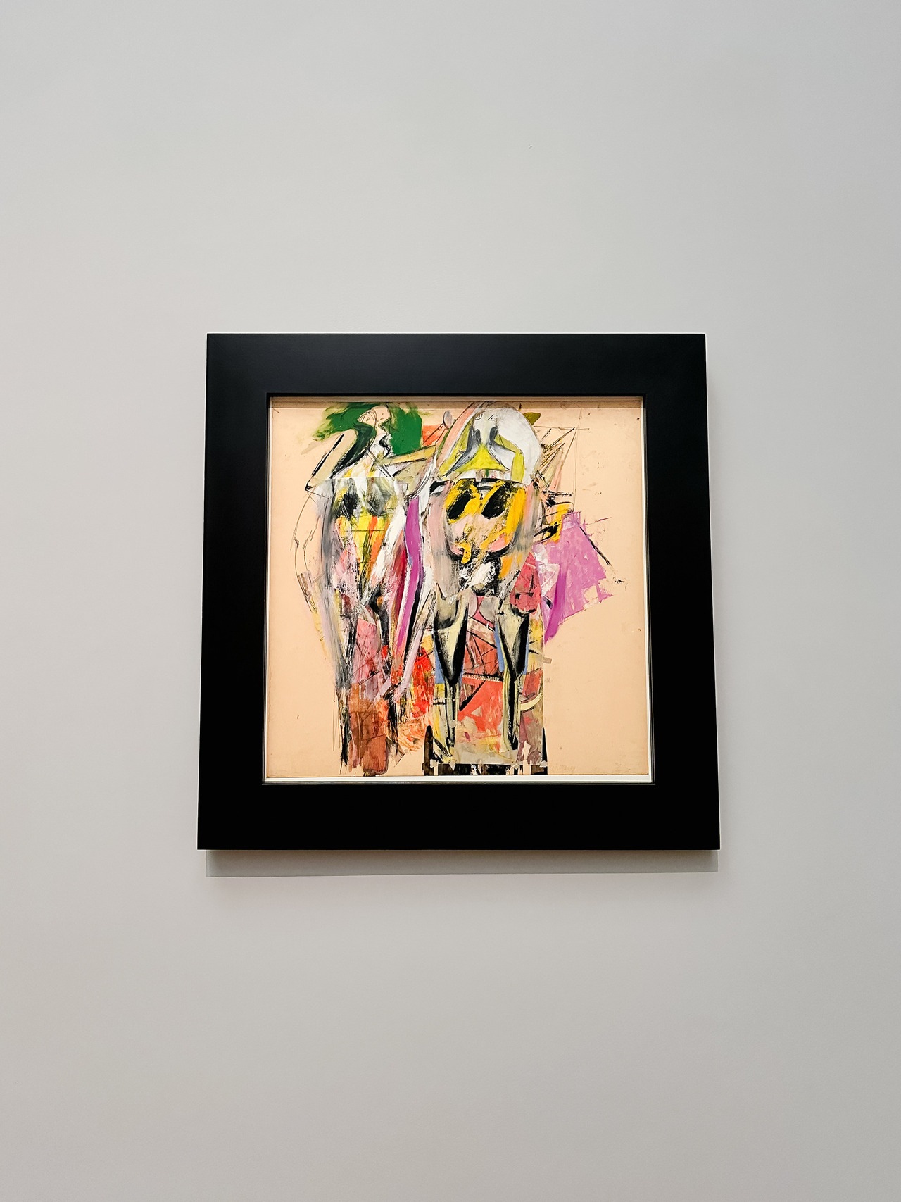 Willem de Kooning painting of two distorted figures in green, yellow, pink and black, displayed in a dark frame.