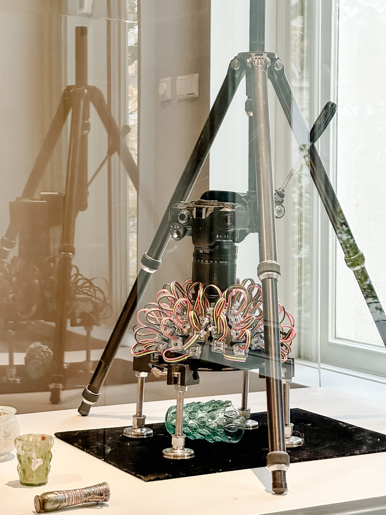 Nikon camera mounted above an ancient glass object with surrounding LED lights for archaeological surface imaging.
