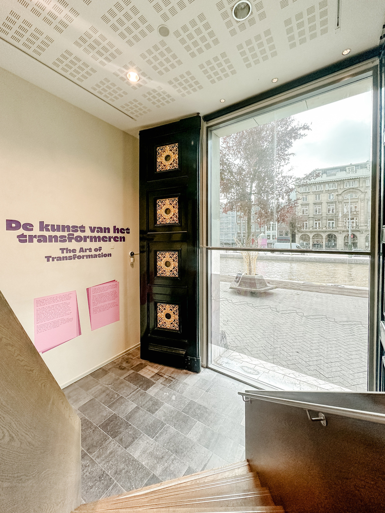 Entrance to The Art of Transformation exhibition at the Allard Pierson Museum in Amsterdam, with purple lettering and a large window overlooking the canal.