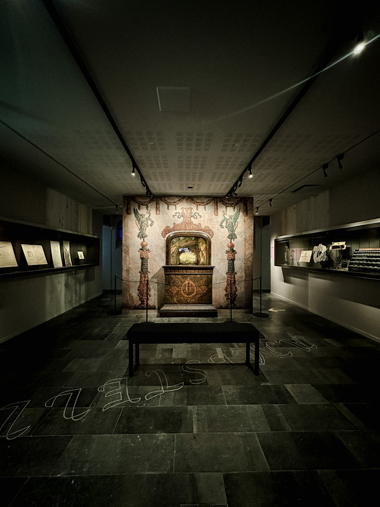 Historic Slingelandt chamber theatre from 1781 displayed in a dark gallery at the Allard Pierson Museum, surrounded by theatrical drawings and stage equipment.