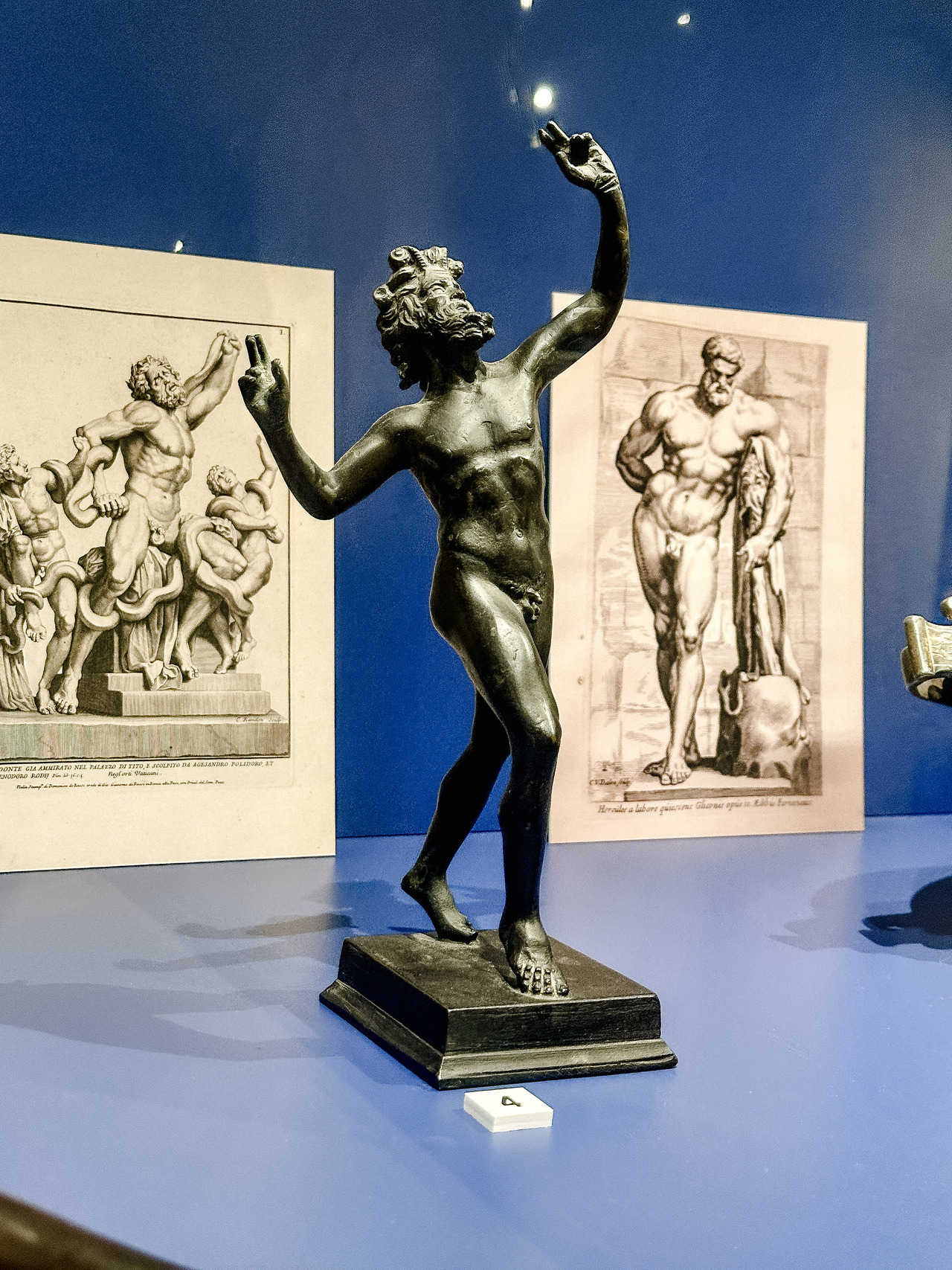 Bronze reproduction of the Dancing Faun from Pompeii, showing a bearded figure with raised arms and one leg lifted, at the Allard Pierson Museum.
