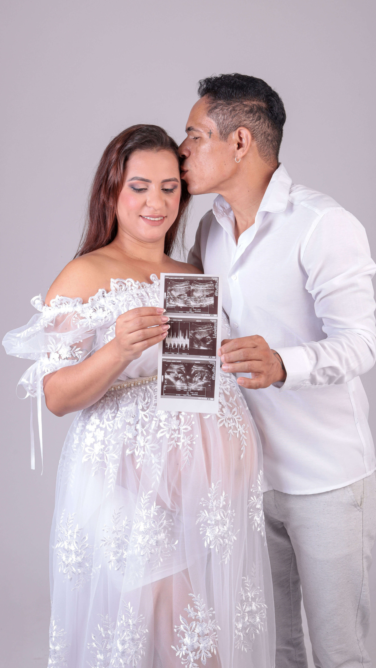 Fotografia de gestante com o pai do bebê segurando uma foto do ultrassom