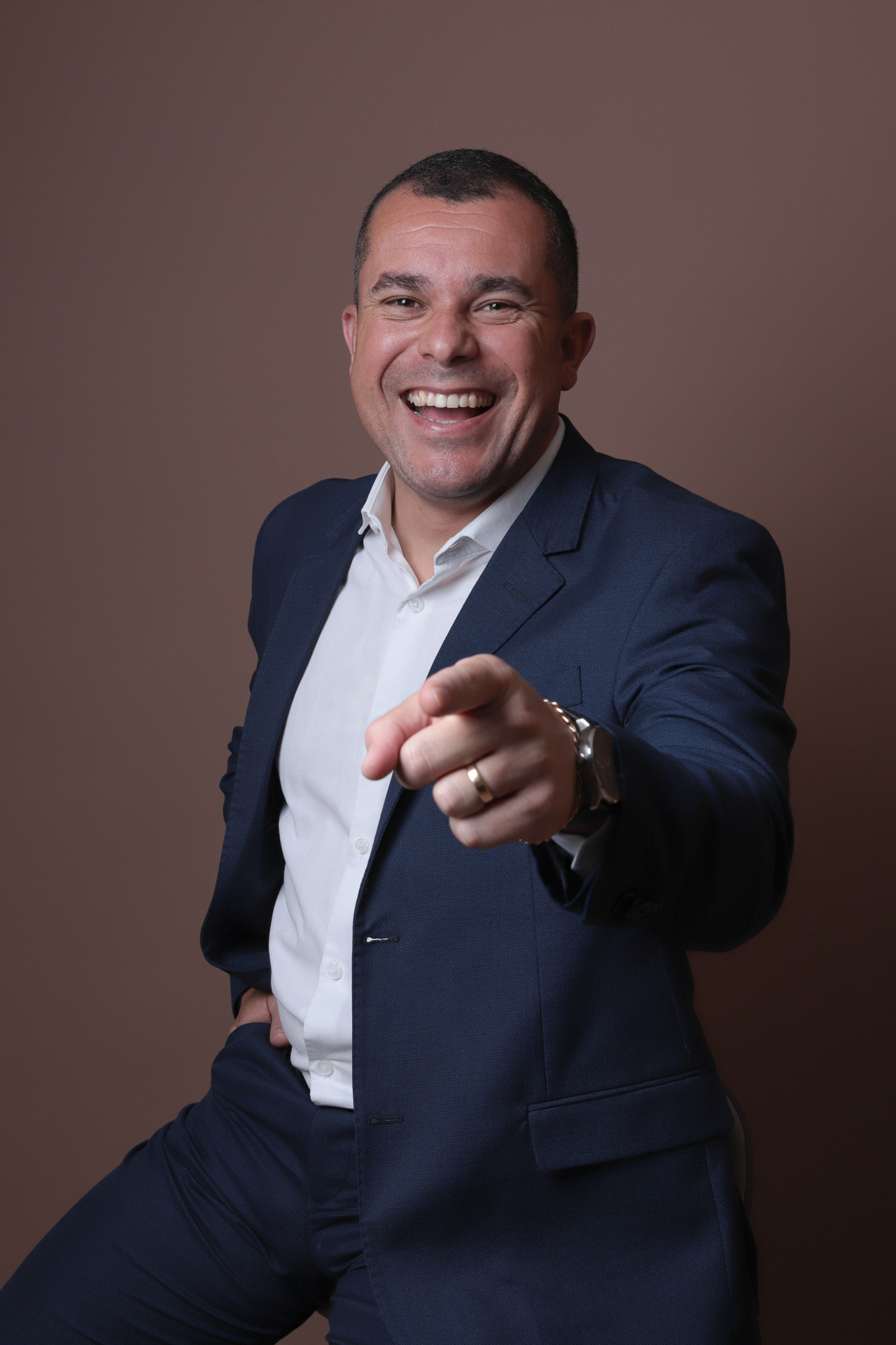 Retrato profissional masculino com expressão espontânea e postura confiante, transmitindo proximidade, leveza e autoridade no posicionamento profissional