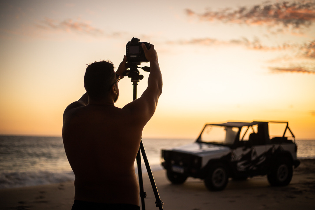 Fotógrafo com tripé fazendo a fotografia de um bugre na areia de saquarema