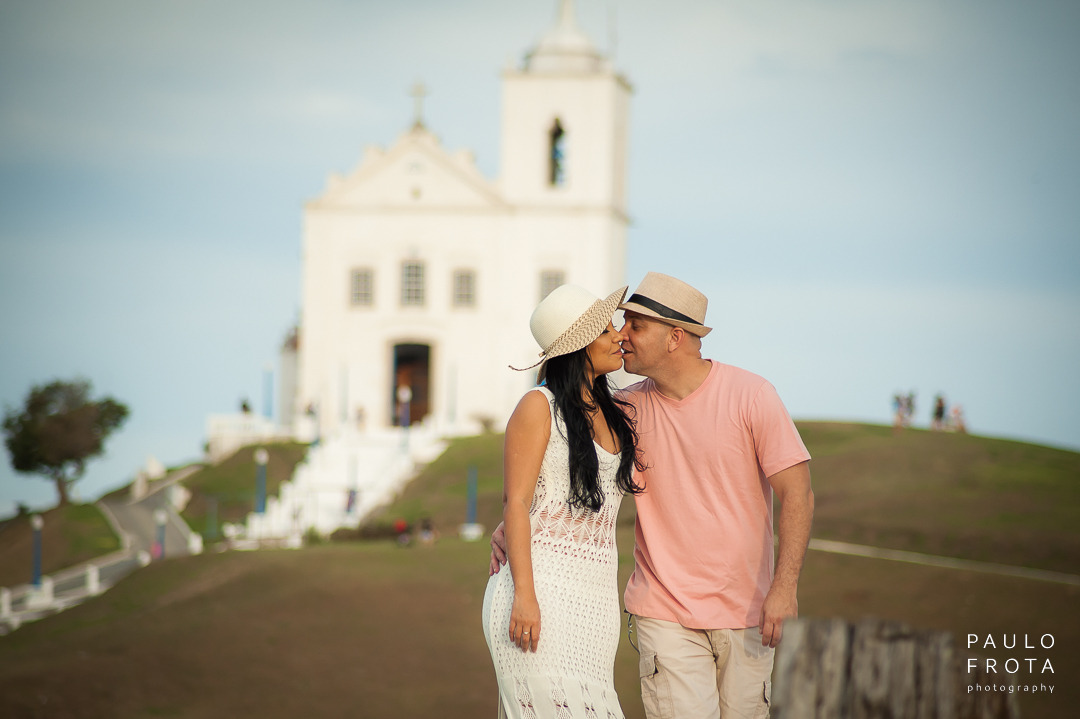 casal se beija. no 3 plano da imagem a igreja de saquarema.