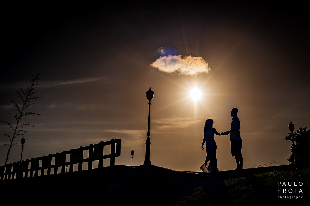 casal de mãos dadas, ela como se estivesse dançando. os dois na silhueta.