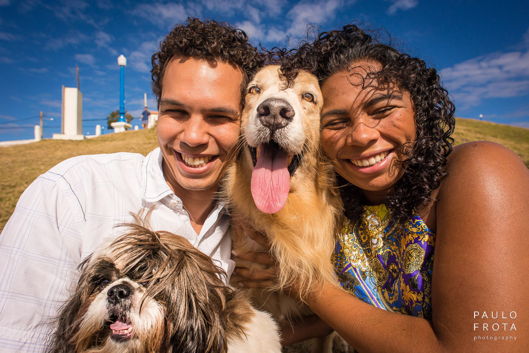 fotografia de ensaio pre wedding com o casal olhando para a a foto com dois cachorros