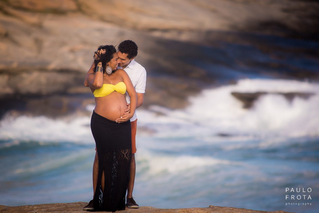casal gestante se abraça. ela na frente dele e se olhando. ensaio na praia da vila em saquarema