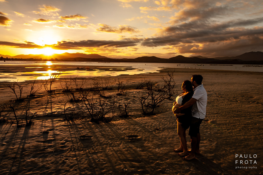 casal em direção ao sol na lagoa de saquarema. Casal em silhueta e o sol refletindo na agua.