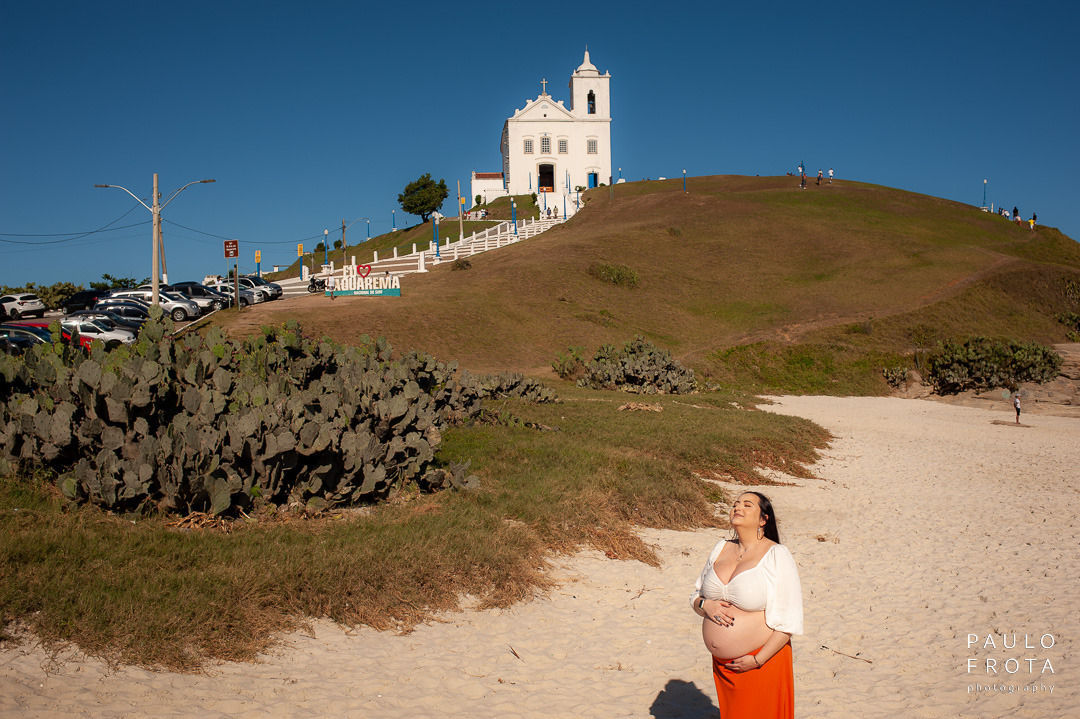 gestante na praia do canto em saquarema. igreja ao fundo
