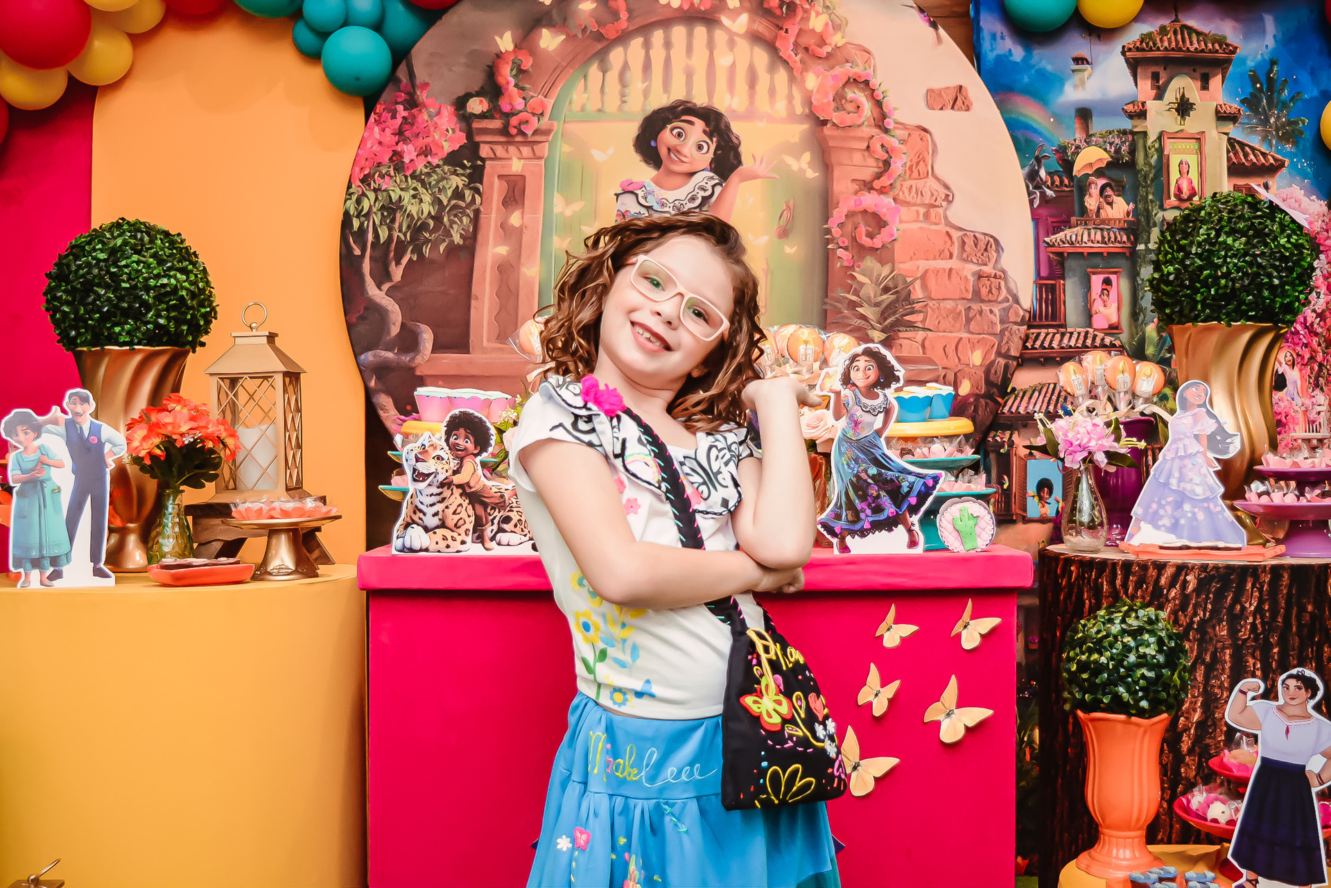 aniversariante posa em frente a mesa decorada do bolo durante festa de aniversário infantil