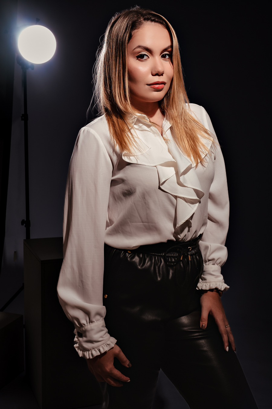 ensaio feminino em estúdio de modelo fotográfica que usa calça preta blusa branca de manga comprida