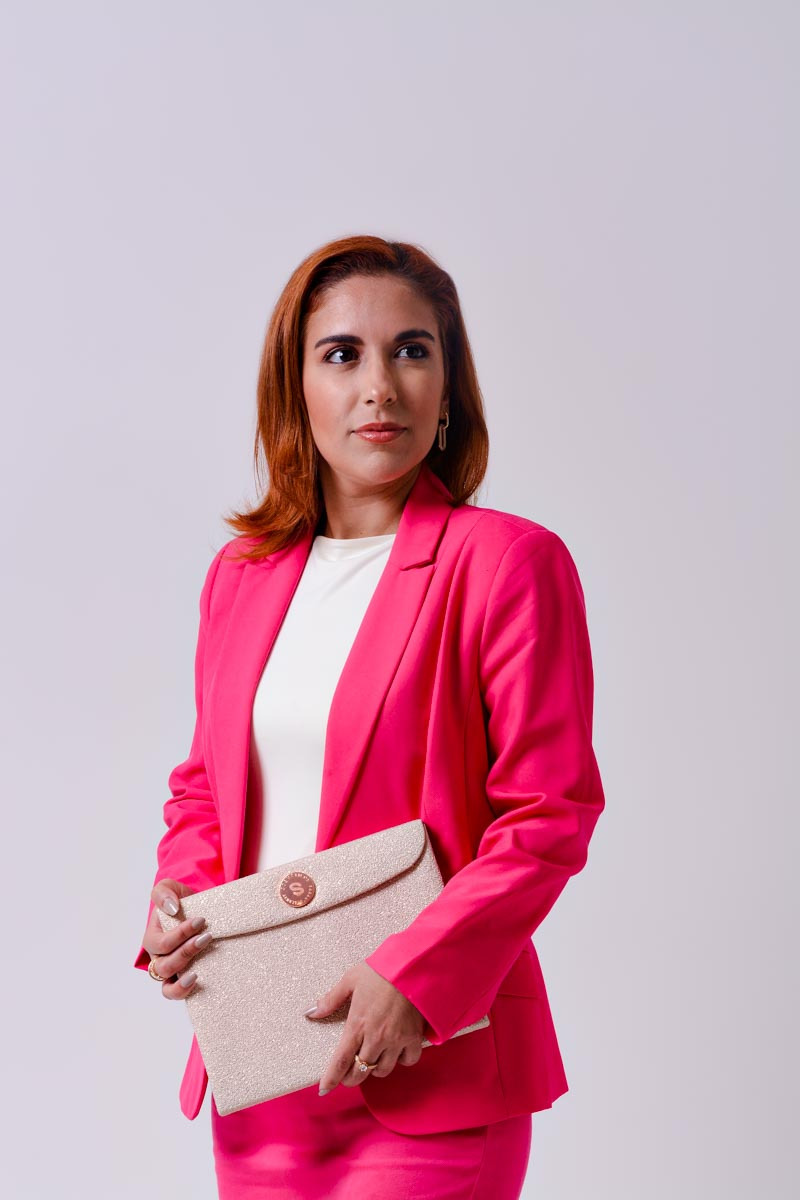 Fotografia de Branding Pessoal para empreendedora de maquiagem e vestuário. Ensaio feminino em estúdio em Niterói. A empreendora segura uma pasta de maquiagem e olha para o lado direito de maneira serena e confiante.