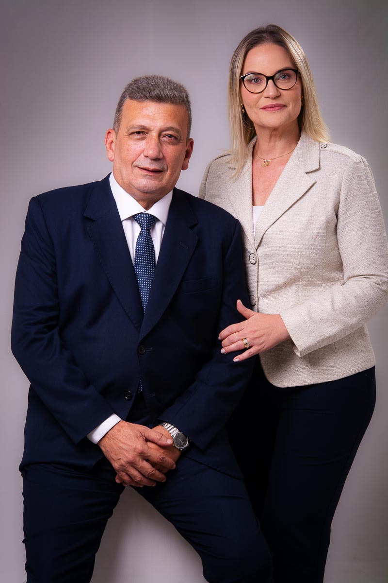 casal de advogados posando para retratos corporativos com fundo neutro cinza