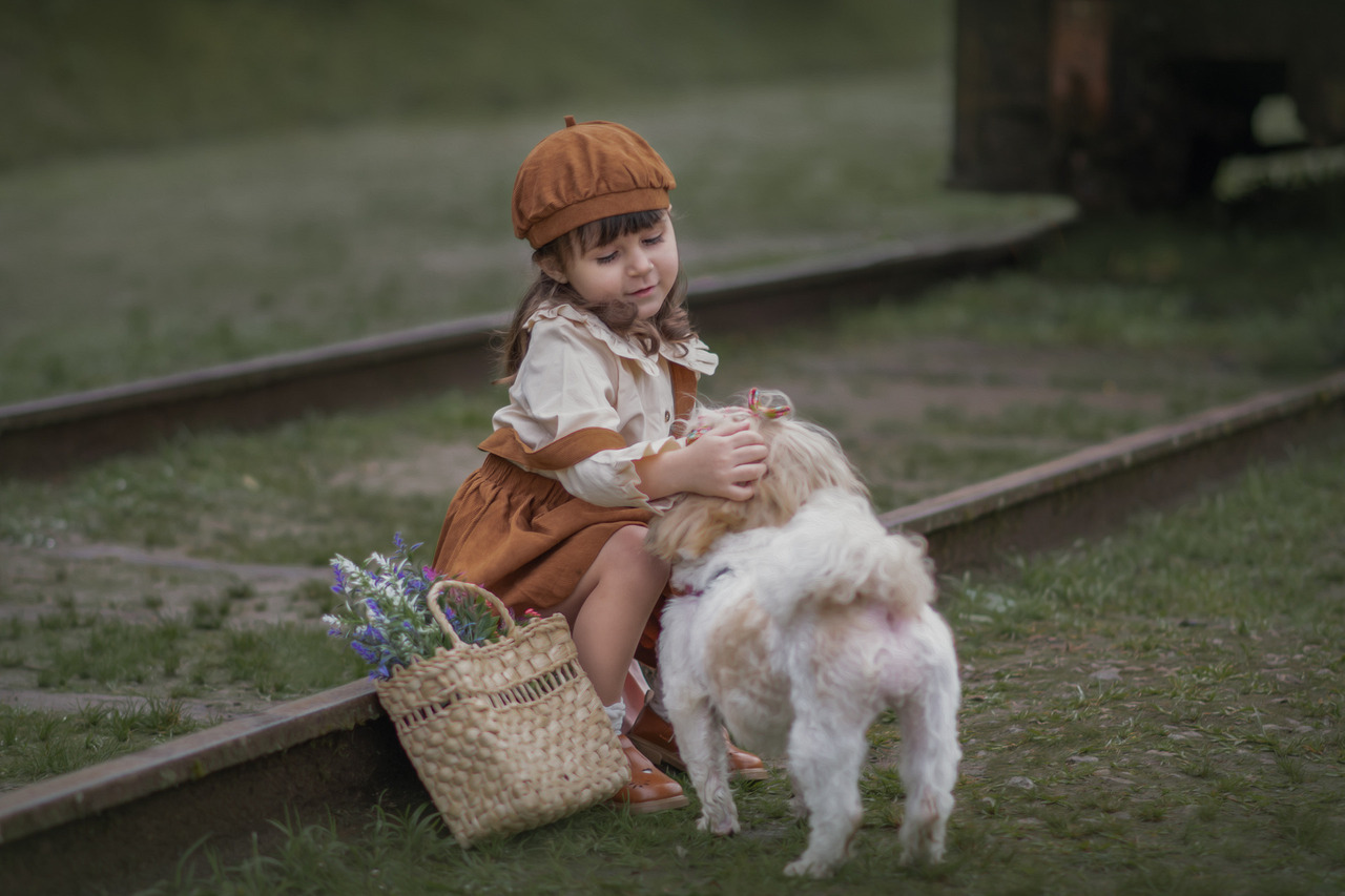 Uma menina, sentada em trilhos de trem, brincando com sua cachorra, durante ensaio fotográfico em Paranapiacaba.