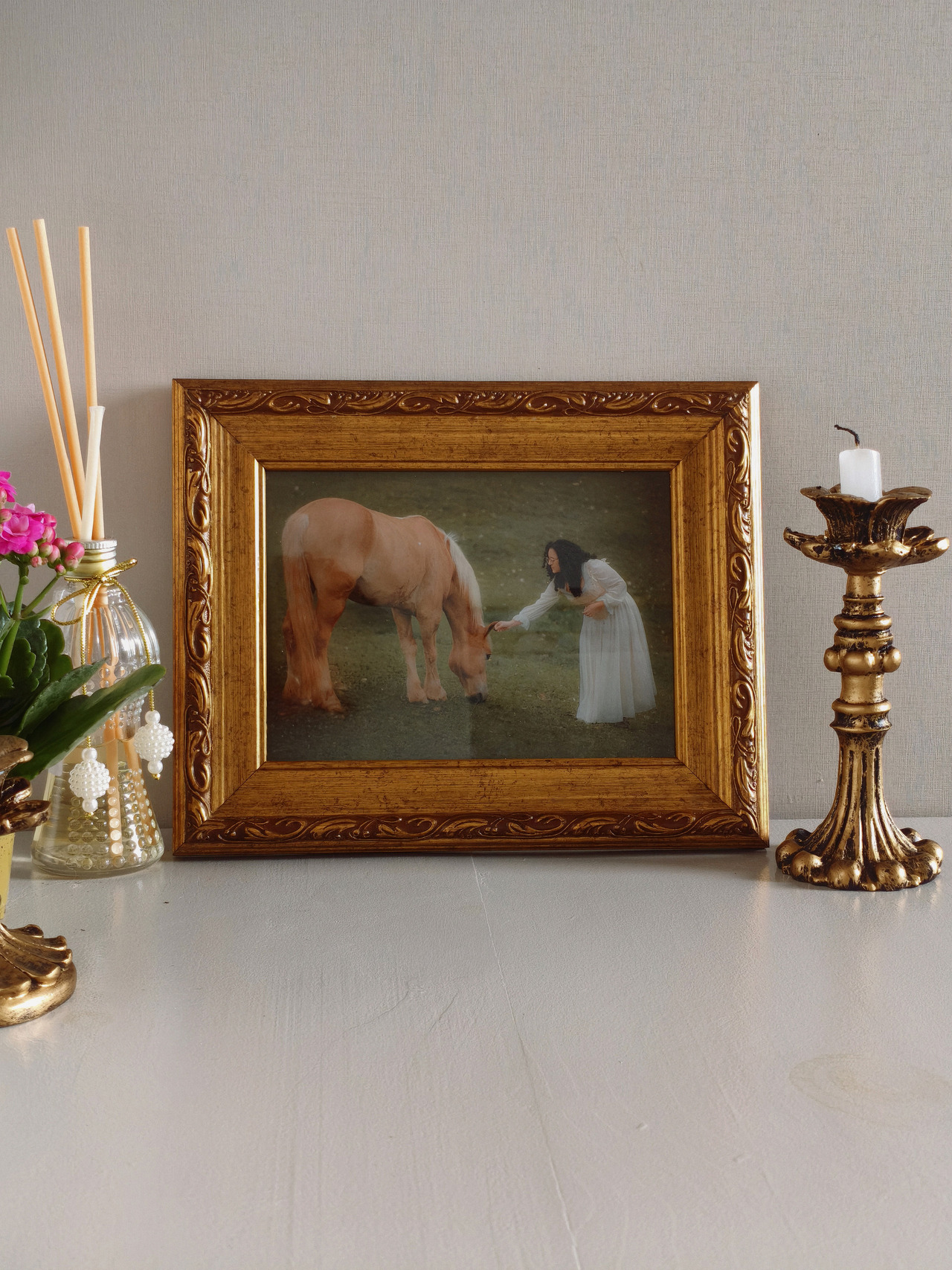 Quadro de fotos com detalhes arabesco ao lado de um castiçal com uma vela.