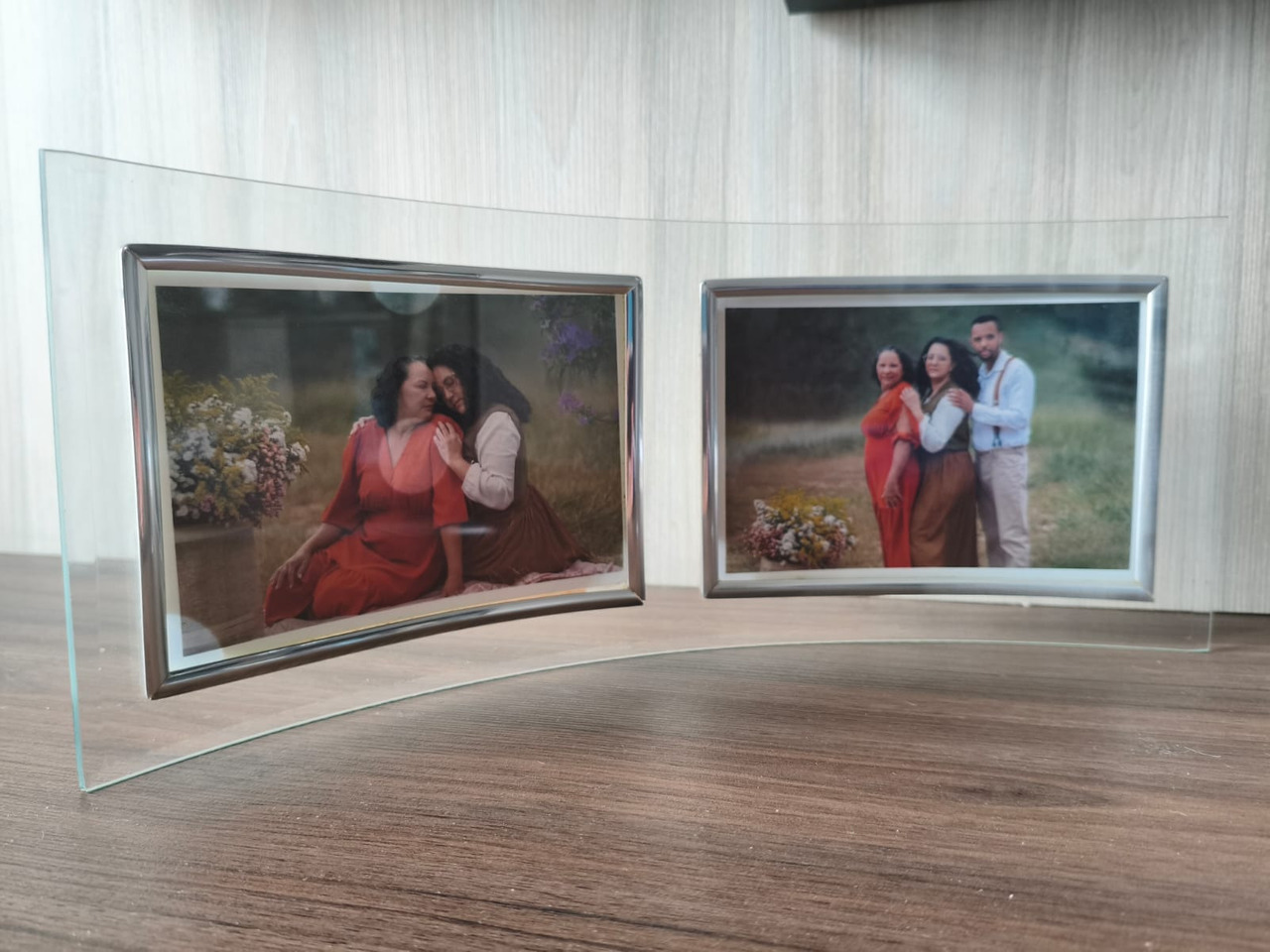 Porta retrato de vidro mostrando de uma lado uma mulher de laranja com uma moça vestida com roupas estilo camponês e do outro lado as duas mulheres ao lado de um homem.