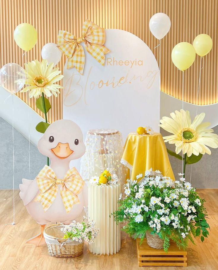 Decoração de festa infantil com cores amarelas e um patinho com gravata de laço xadrez.
