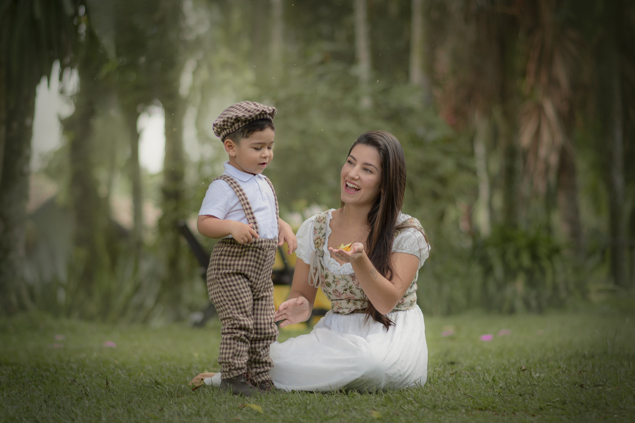 Uma mulher brincando na grama com seu filho pequeno, durante o ensaio fotográfico de dia das mães.
