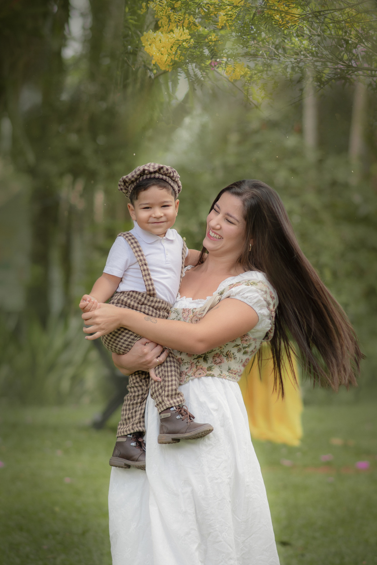 Uma mulher brincando de girar com seu filho, durante o ensaio fotográfico de dia das mães ao ar livre.
