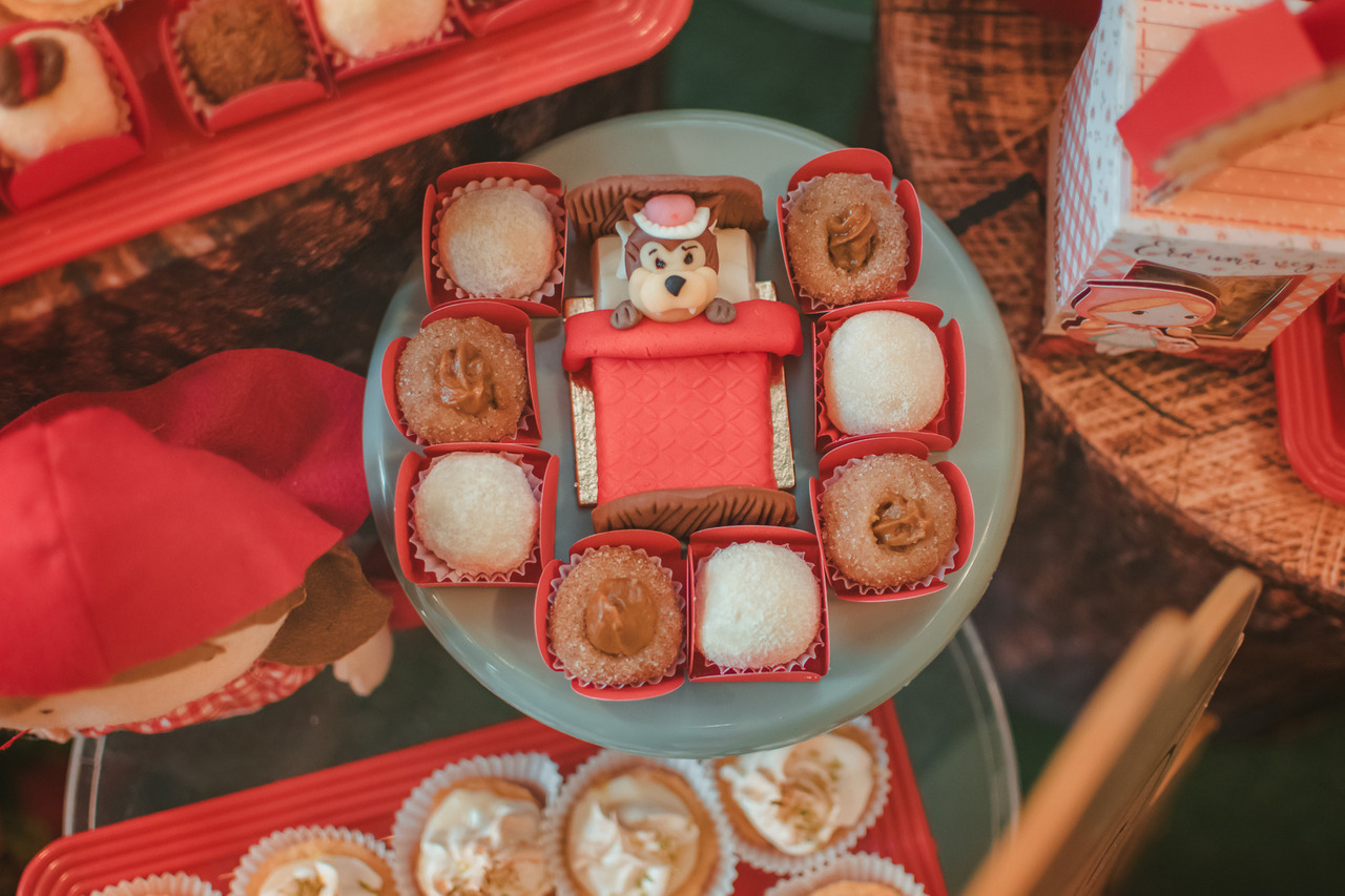 Doces personalizados para festa de 1 ano com tema Chapeuzinho Vermelho, decorados com uma caminha e o Lobo Mau deitado.