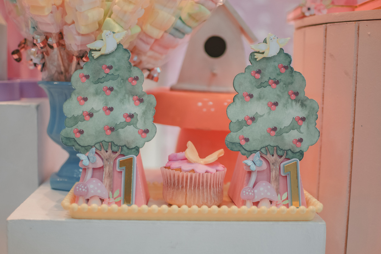 Caixa com desenho de árvore e coopcake com decoração de borboleta, para festa de aniversário de 1 ano.