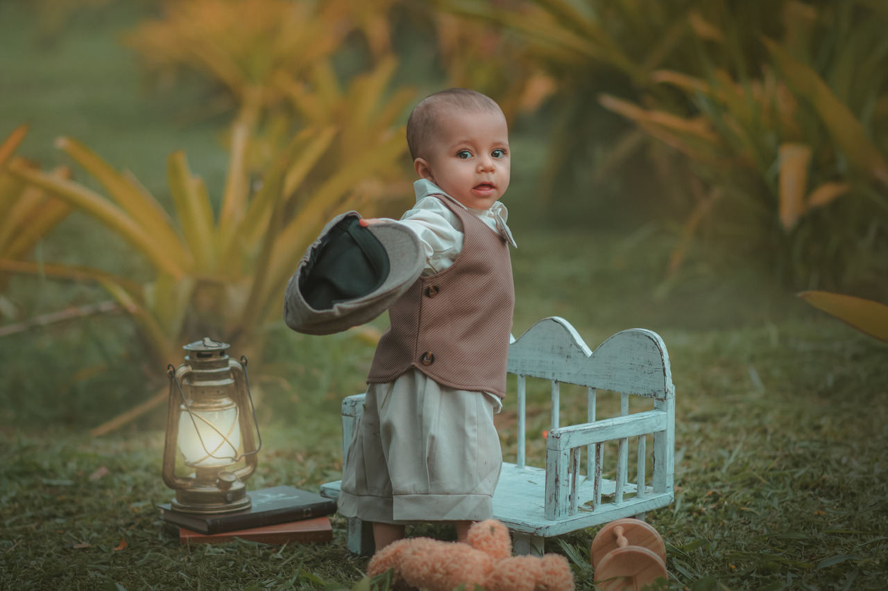 Uma menino, mostrandoo uma boina, durante seu ensaio fotográfico de 1 ano.