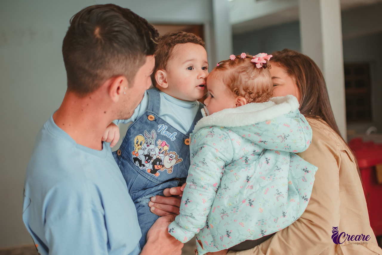 Dois bebês dando beijo na testa do outro, durante aniversário de 1 ano em casa.