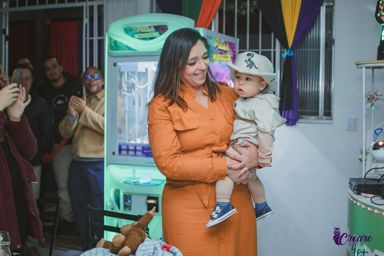 Uma mulher com seu bebê no colo, durante festa de aniversário de 1 ano.