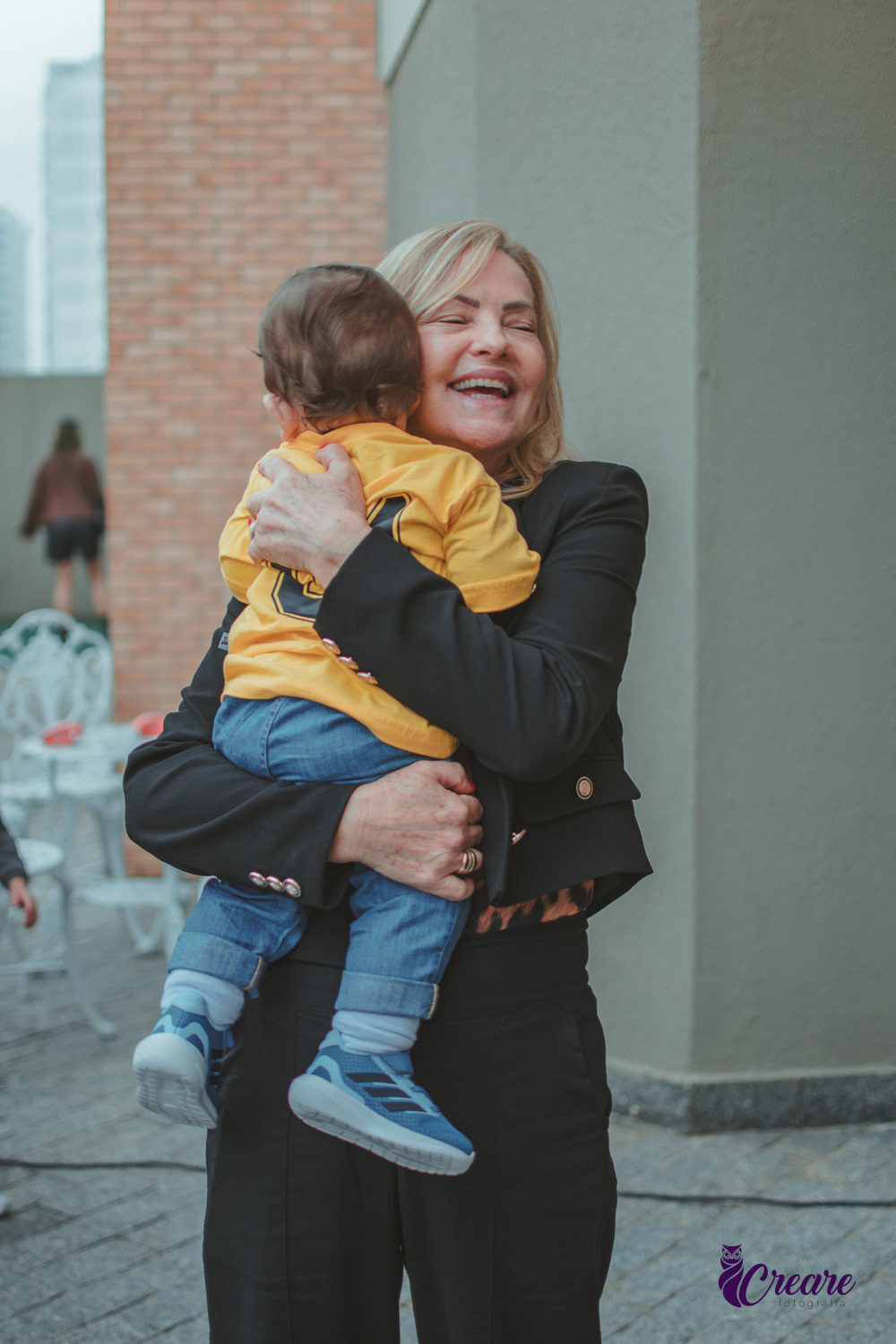 Uma avó abraçado seu neto de 1 ano, durante festa de aniversário.