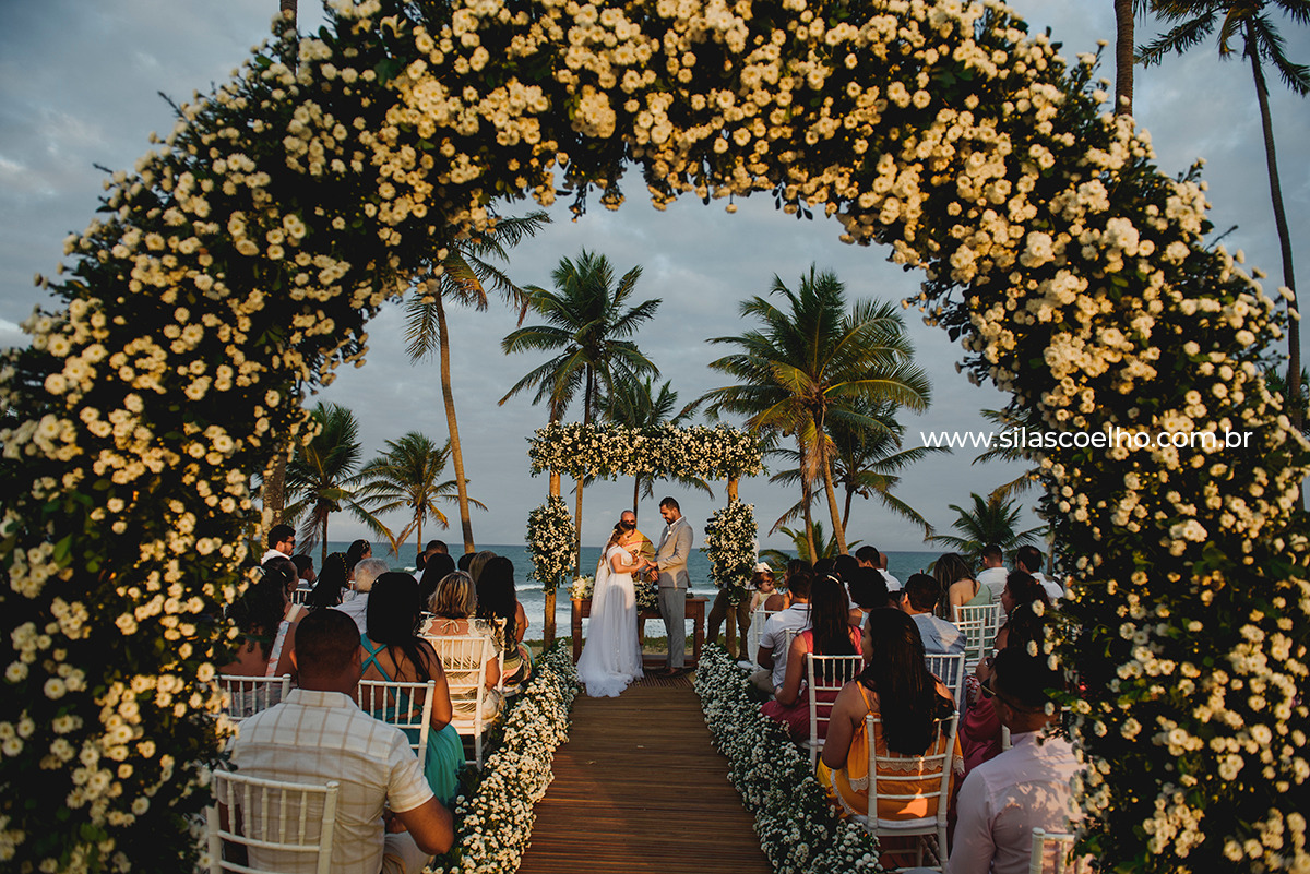 Troca de alianças dos noivos na ceriônia de casamento. Destination Wedding na praia e no pôr do sol