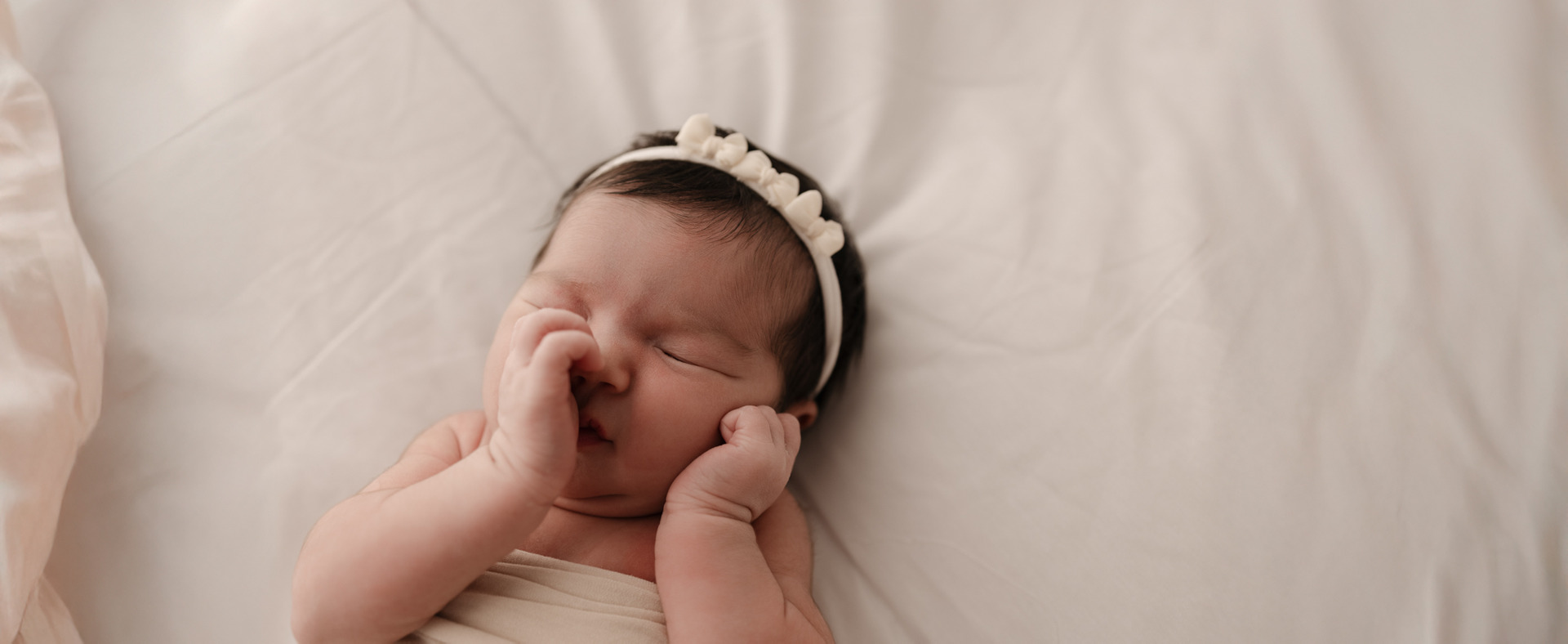 IMAGEM 03 — Base neutra em ensaio newborn: bebê dormindo sobre tecido cru, faixa discreta, sem cor de destaque