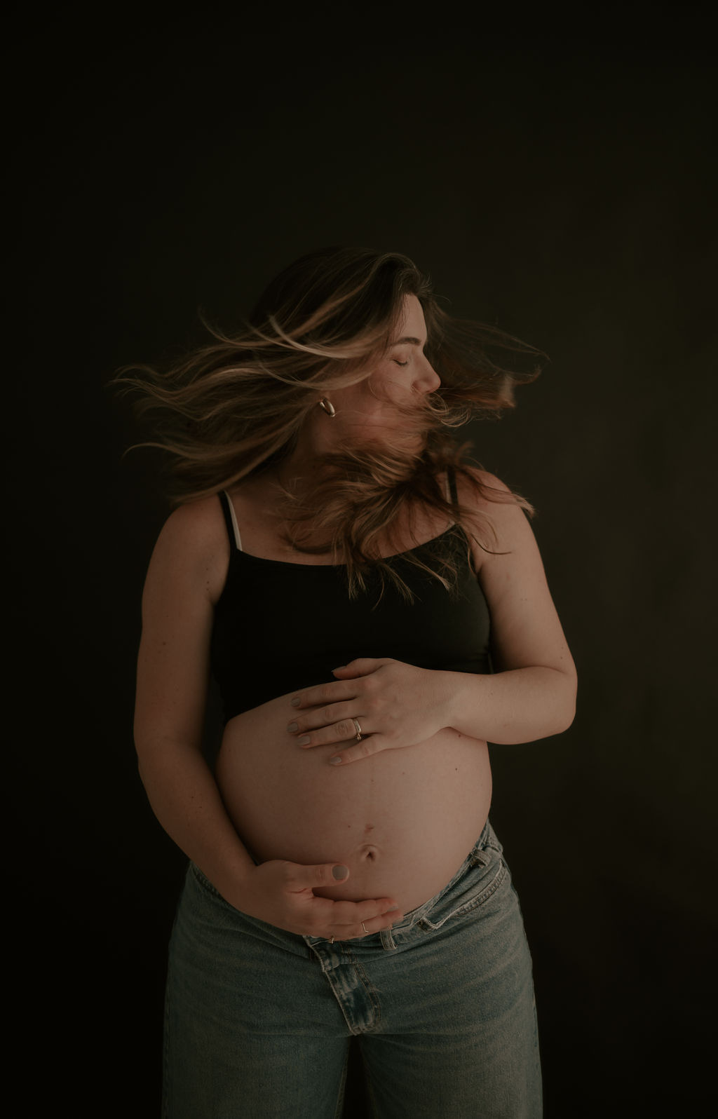 Gestante com as mãos na barriga, ensaio de estúdio
