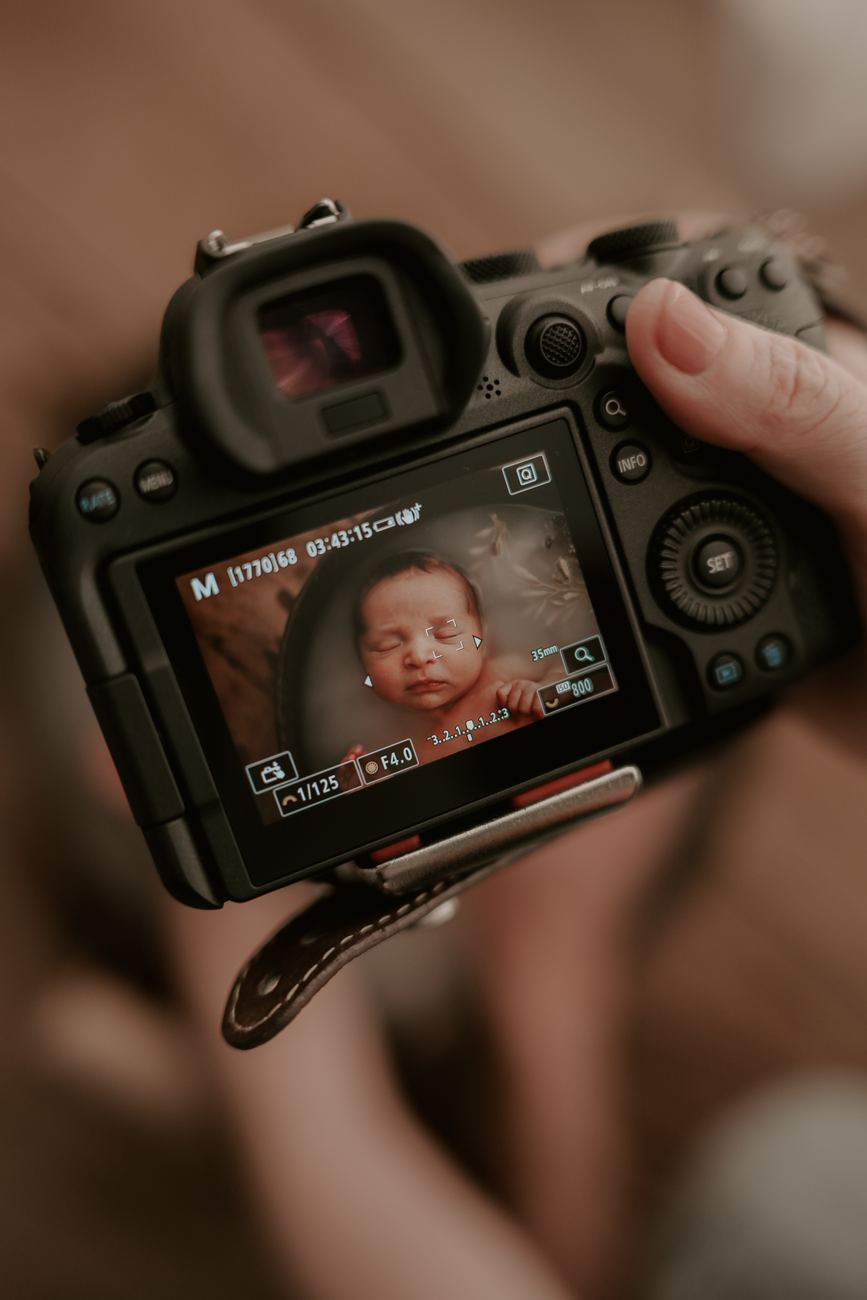 A tela da câmera mostra o bebê recém-fotografado, nas mãos de quem fotografa