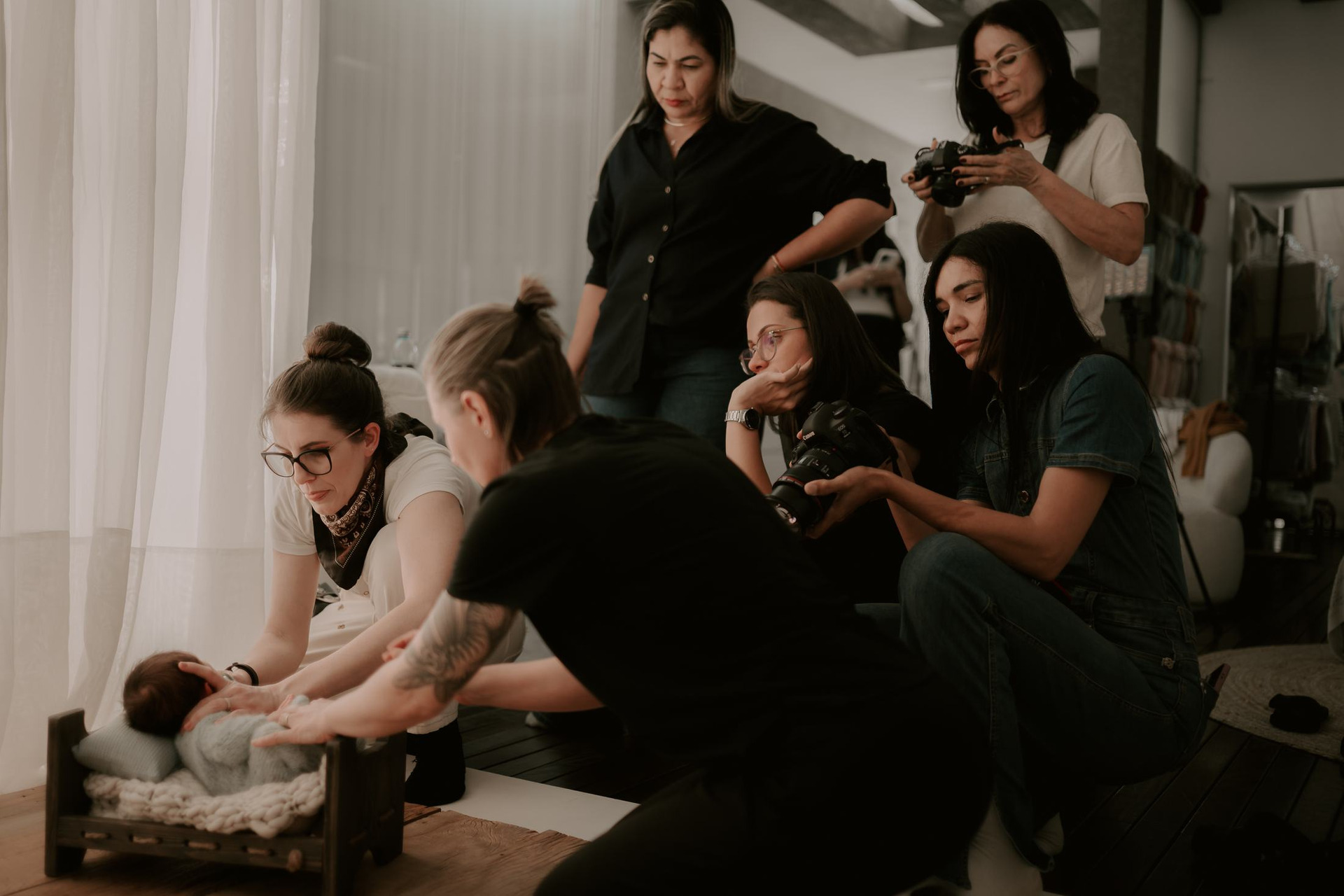 No workshop de setembro, Bel posiciona o bebê enquanto as alunas acompanham a um passo de distância, com as câmeras nas mãos