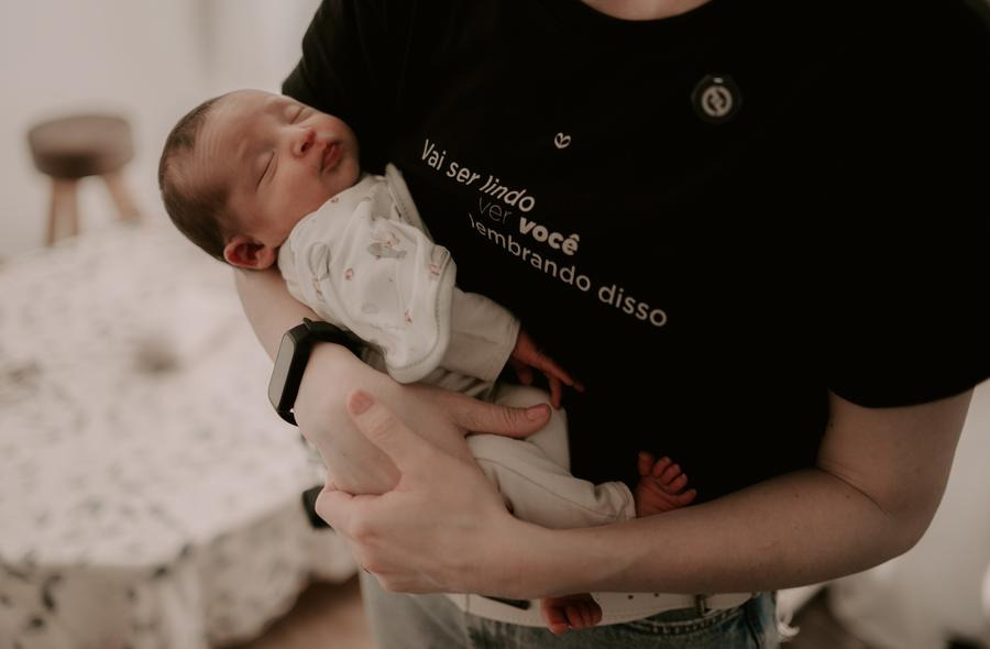 Bel segura o bebê no colo, de perto