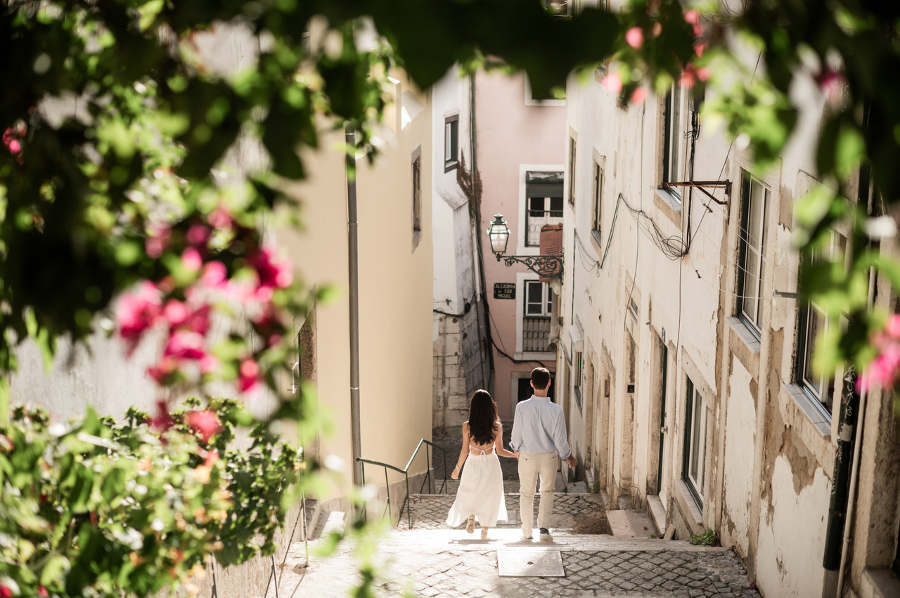 Newly engaged couple walking through the narrow streets of Alfama, Lisbon, during their engagement session