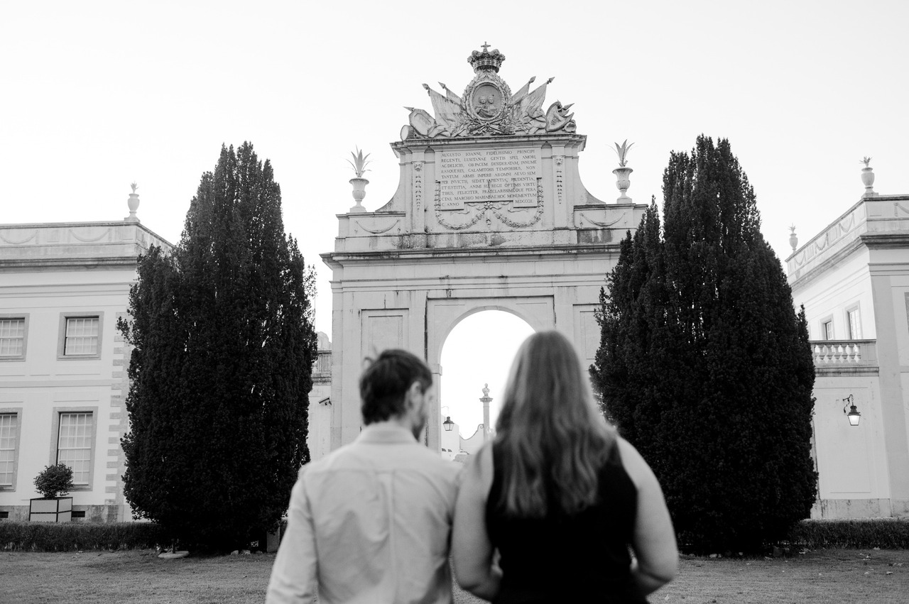 Couple walking toward the neoclassical arch of Palácio de Seteais in Sintra at sunset after a proposal