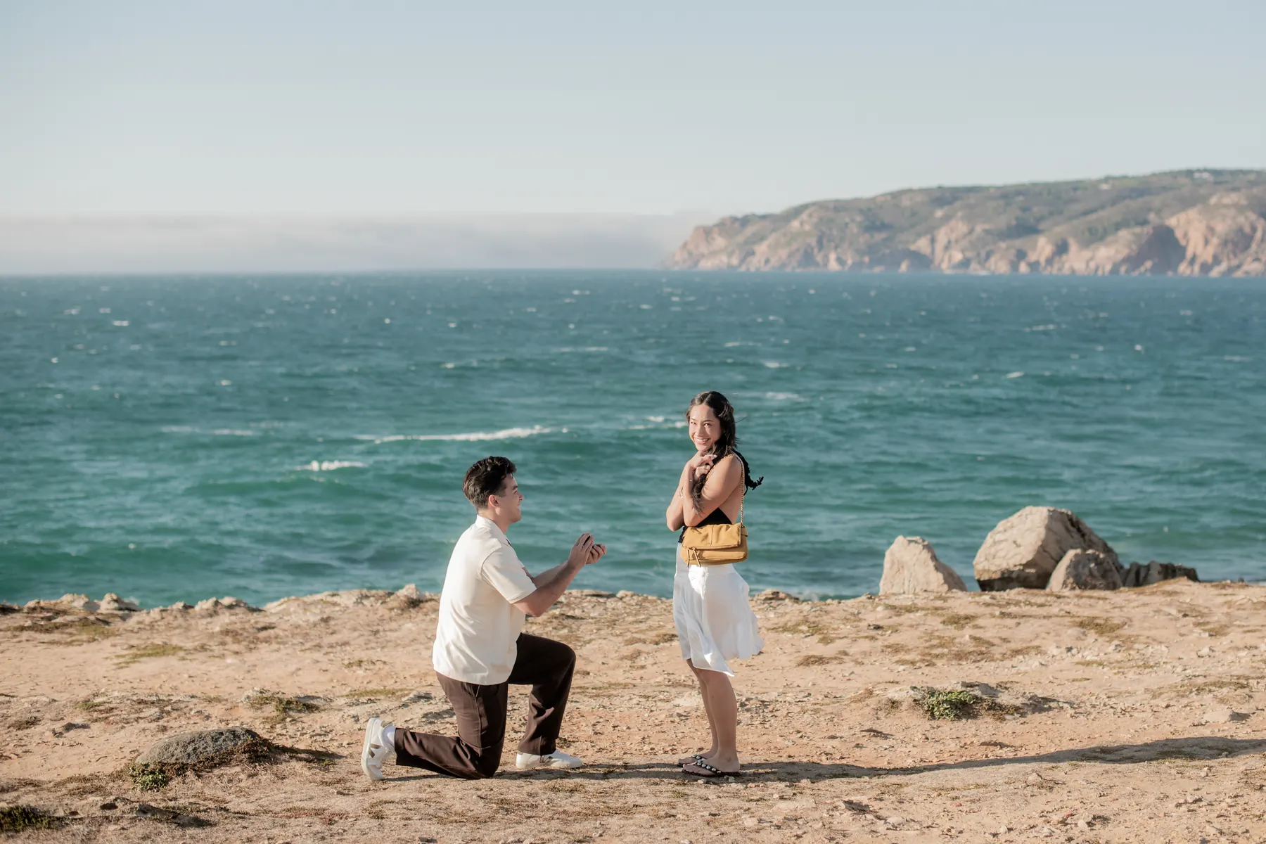 Surprise proposal on one knee on the clifftop above the Atlantic near Praia do Guincho, Cascais proposal photography by Mariana Castanheira