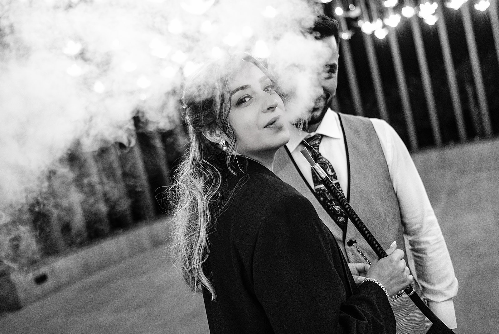 olhar sensual da noiva pelo meio do fumo com noivo a sorrir ao fundo