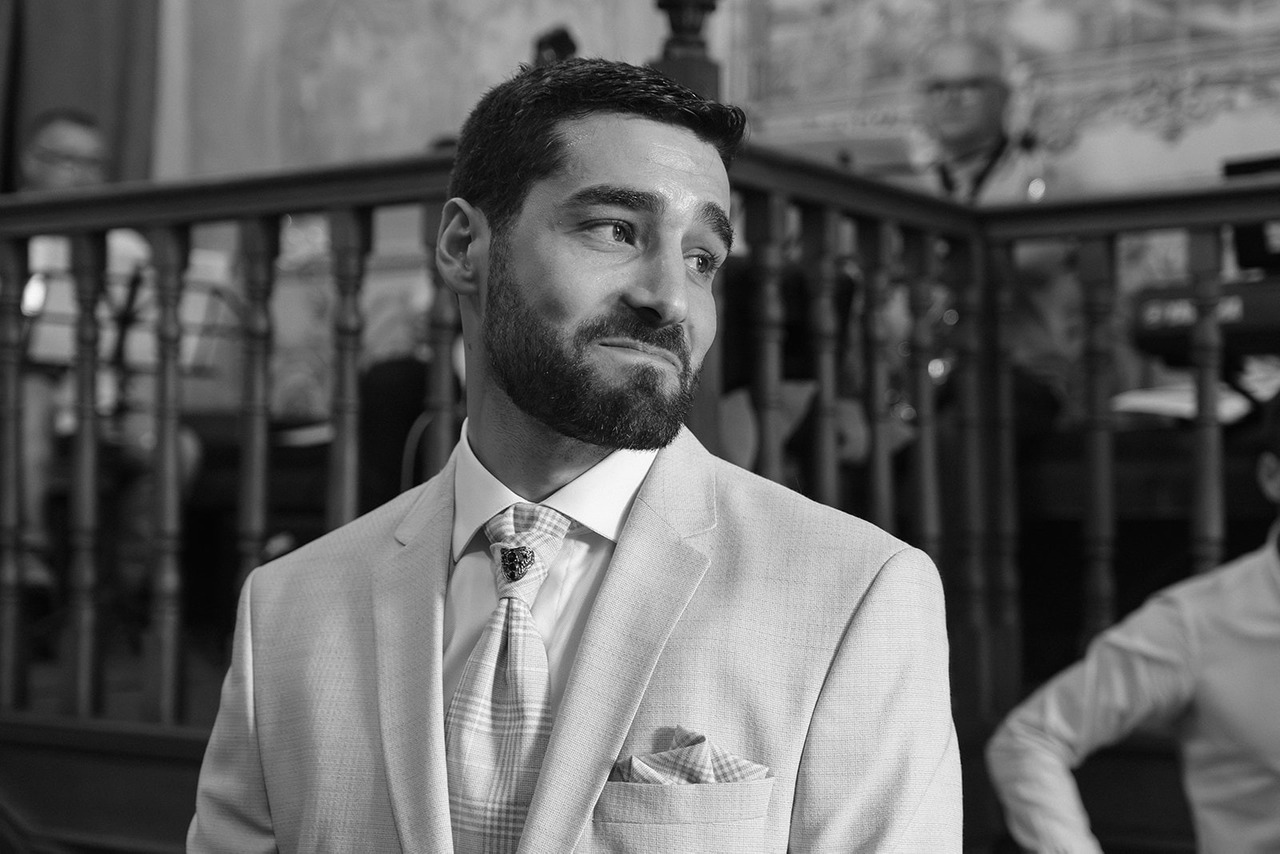 Noivo de pé, em preto e branco, a olhar para a entrada da igreja no momento em que a noiva chega. Foto por Filipe Santos, 2025.