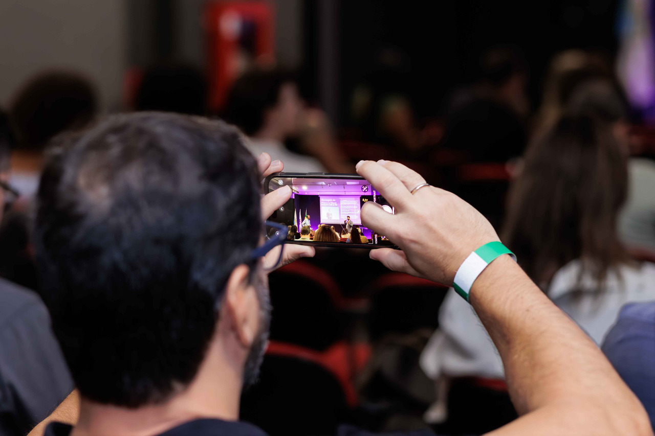 Homem na platéia fazendo uma foto do palco da premiação com o celular