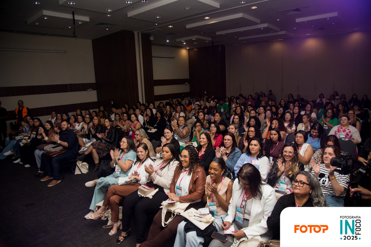 Fotógrafos e participantes do congresso de fotografia InFoco 2025 em Nova Iguaçu lotam o auditório e aplaudem durante palestra, demonstrando engajamento e entusiasmo pelo evento.