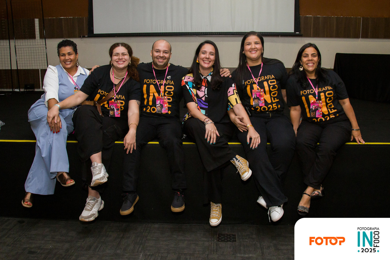 Equipe do congresso de fotografia InFoco 2025 reunida no palco, em Nova Iguaçu, sorrindo e celebrando o evento. Foto de organização e colaboradores do maior congresso de fotografia da Baixada Fluminense
