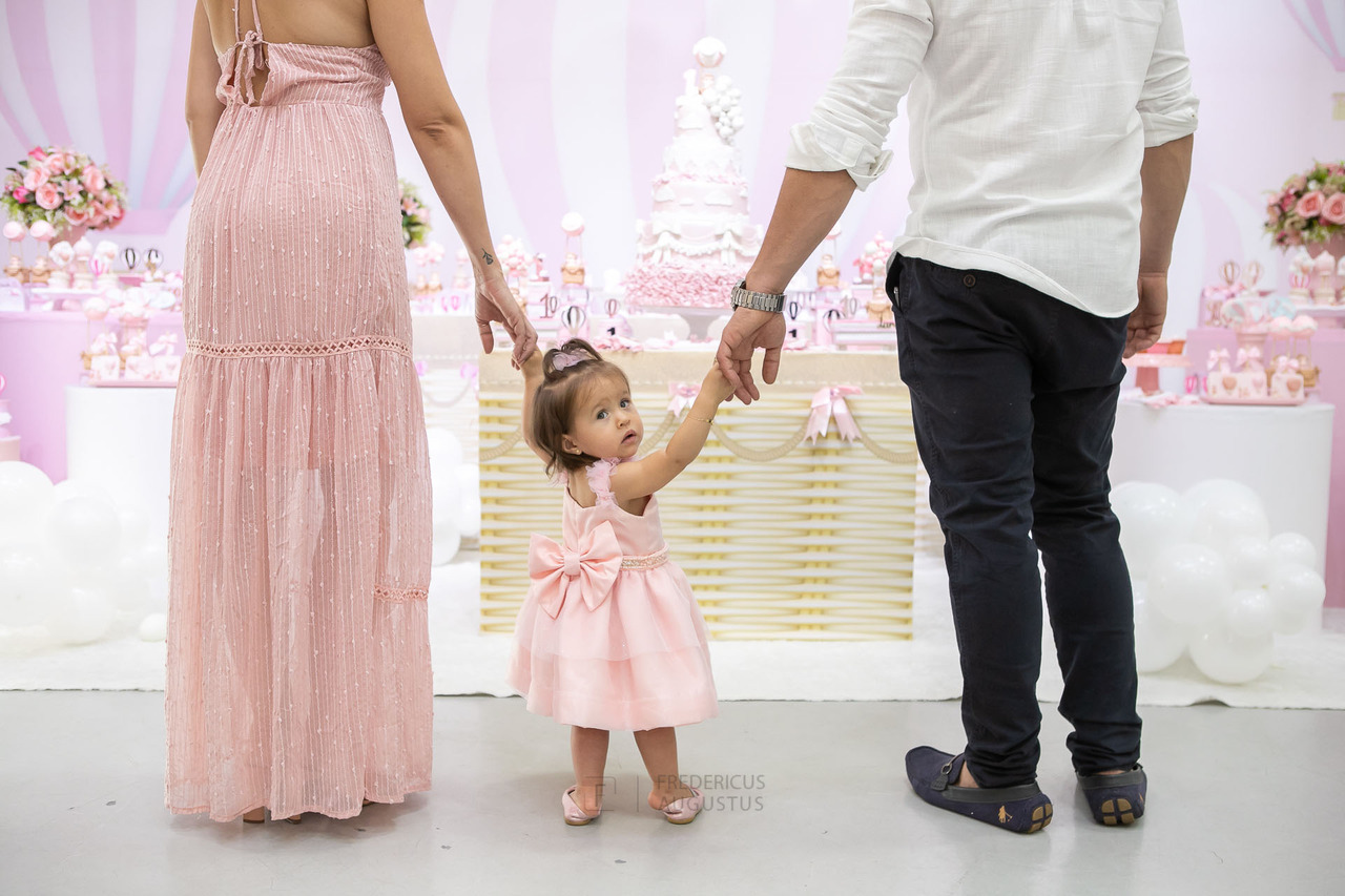 Foto da aniversariante com lindo vestido na mesa do bolo com seus pais