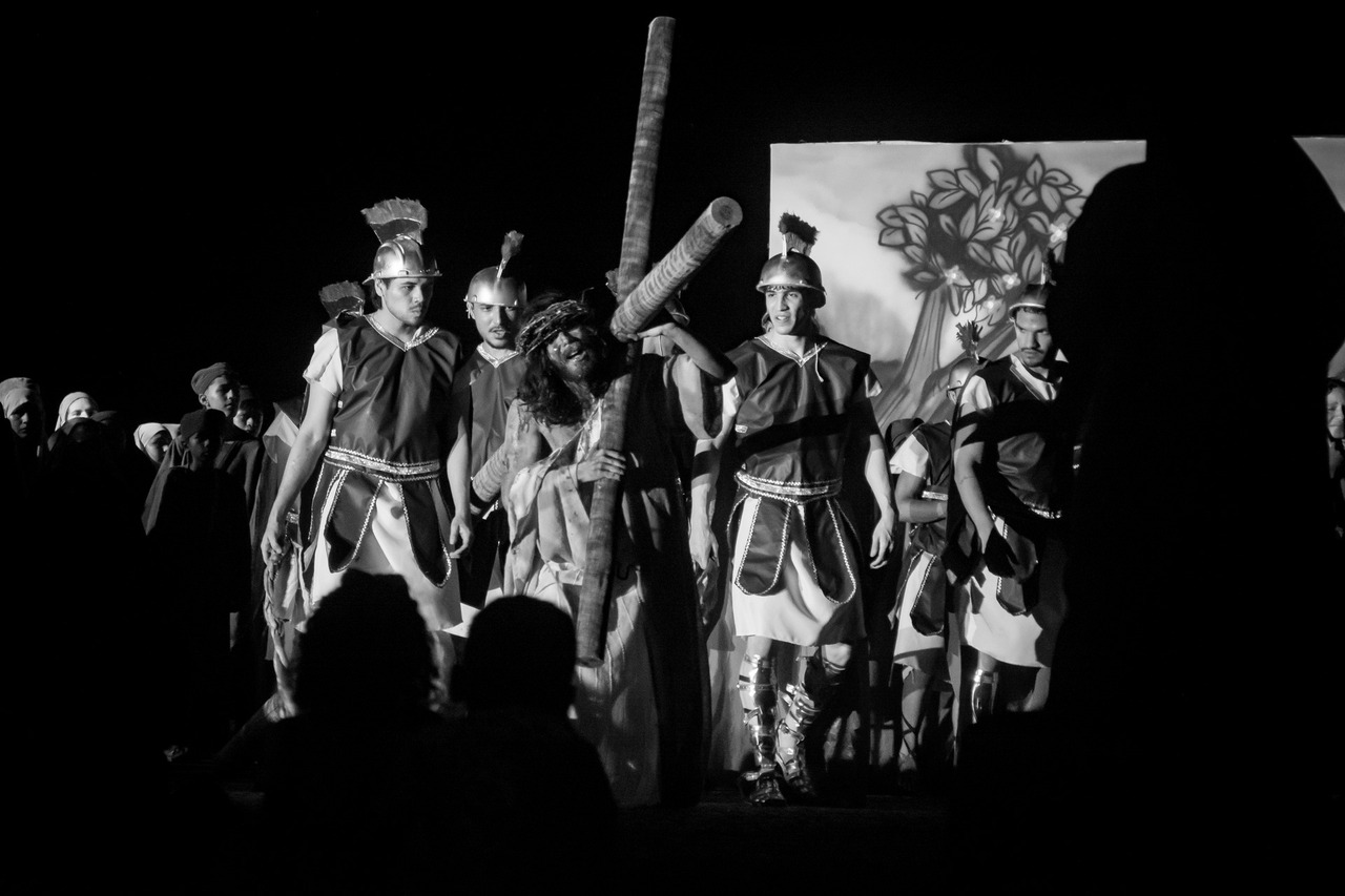 Fotografia em preto e branco de Jesus Cristo crucificado, com a cabeça baixa, em uma cena dramática da Paixão de Cristo em Palmas.