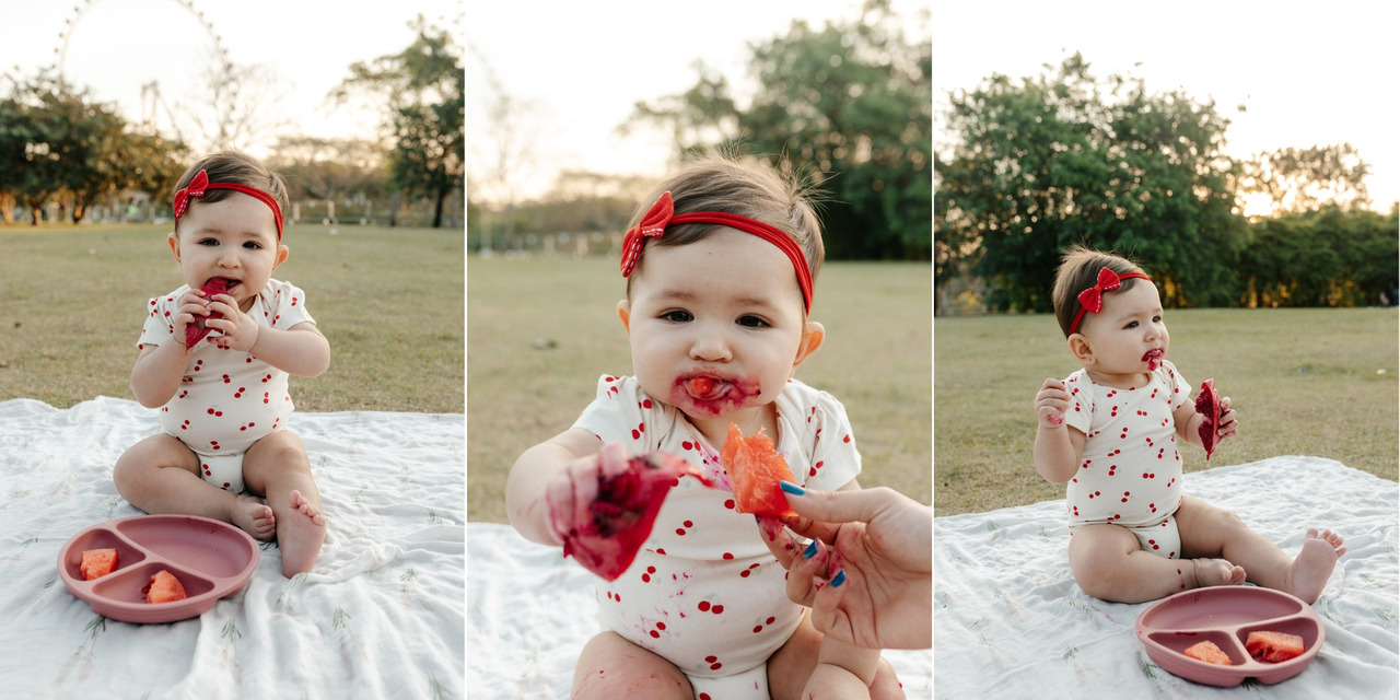 fotografia de bebê comendo frutas no parque